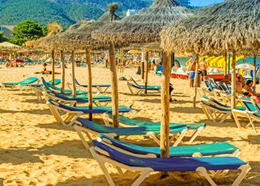 MAGALUF, MALLORCA, SPAIN, July 18 2016: Sun beds and beach umbrellas on sandy beach at and of the day at Magaluf, Mallorca, Spain. clipart