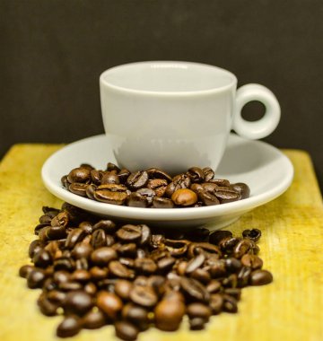 Tahta yüzeyde kahve çekirdekleri ile çevrili bir fincan espresso..