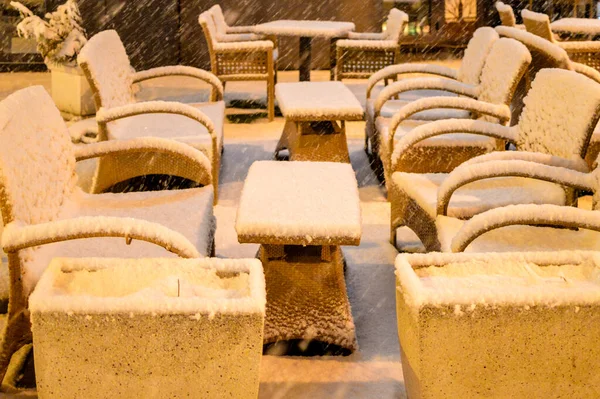 A caffe bar furniture covered with snow, night time shot, street light.