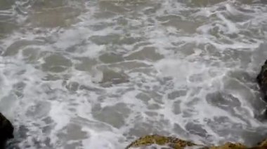 Güçlü deniz dalgaları taşların üzerine sıçrar..