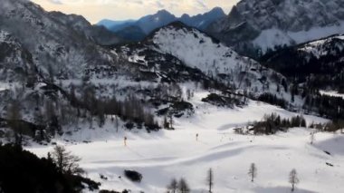 Avusturya 'nın Nasffeld kentinde kış günü kayak merkezinde kayakçılarla ve karla kaplı etrafındaki dağlarla, yukarıdaki bulutlu gökyüzüyle panoramik olarak görülebilir..