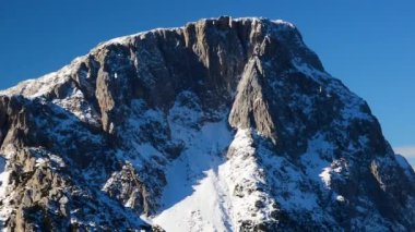 Avusturya 'nın Nassfeld kentindeki güneşli kış gününde kayalık dağın üzerindeki hava manzarası kısmen karla kaplıydı..