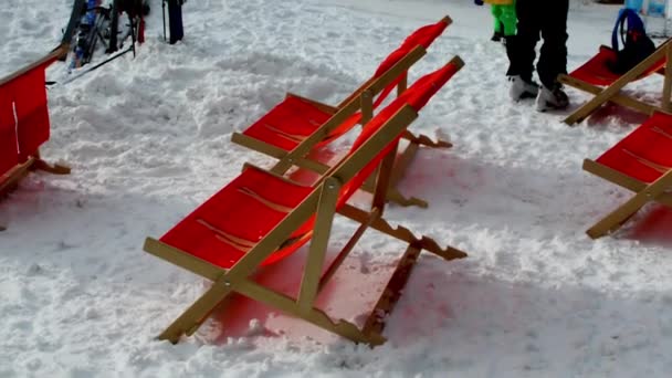 Nassfeld Austria 2019年1月9日 太陽の椅子 雪の中に残されたスキー用具 オーストリアのナッソーフィールドを移動する小さな大人のスキーヤーとスキー場の底のシーン — ストック動画