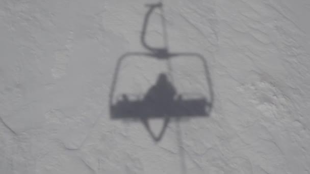 スキー場上部への旅行中に雪でスキーリフトに座っているスキーヤーの影 — ストック動画