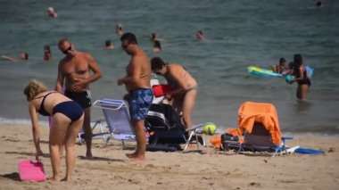 CAMBRILS, SPAIN, 17 Ağustos 2018: İspanya 'nın Cambrils kentindeki sıcak yaz gününde iki erkek ve bir kadın Golden Sandy Plajı' nda oynuyorlar.