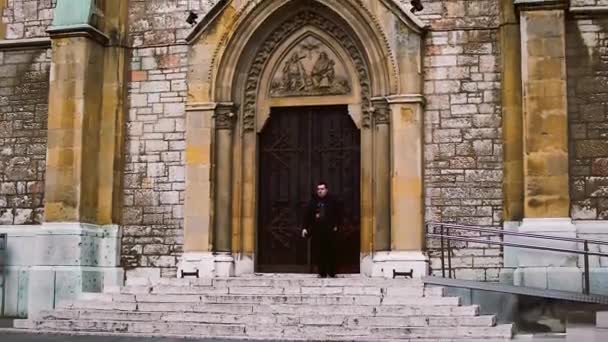 2019年2月26日 一名男子站在波斯尼亚和黑塞哥维那萨拉热窝圣心大教堂前吸烟 — 图库视频影像
