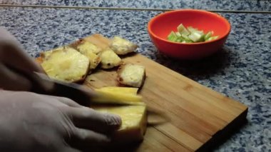 Bir insan ananas meyvesini dilimliyor. Muhtemelen taze meyve suyu için. Tahta üzerinde keskin bir bıçakla..