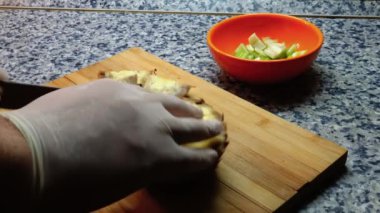 Bir insan ananas meyvesini dilimliyor. Muhtemelen taze meyve suyu için. Tahta üzerinde keskin bir bıçakla..