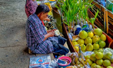 Samut Songkhram Eyaleti, Tayland, 01 Ocak 2020: Bir adam Samut Songkhram Eyaleti, Tayland 'da yüzer markette meyve satmak için temizlik ve hazırlık yapıyor.
