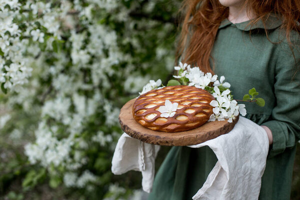 Pie with cottage cheese in the hands of a child is decorated with Apple blossom.