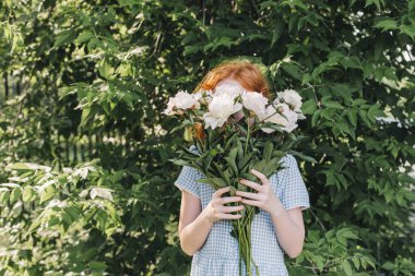 Kızıl saçlı kız yüzünü bir buket şakayıkla kapladı..