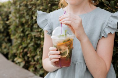 Çocukların elinde, soğuk limonatalı plastik bir bardak..