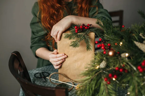 赤い髪の女の子は トウヒの小枝と人工的な赤い果実の小枝で飾られたクリスマスの贈り物を保持しています — ストック写真