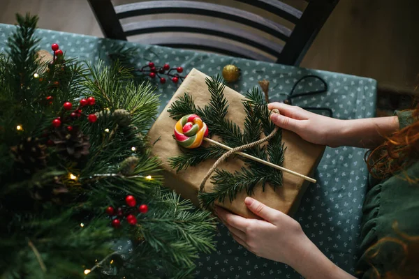 あなた自身の手でクリスマスギフトを梱包する1色のキャンディーとトウヒの小枝 — ストック写真