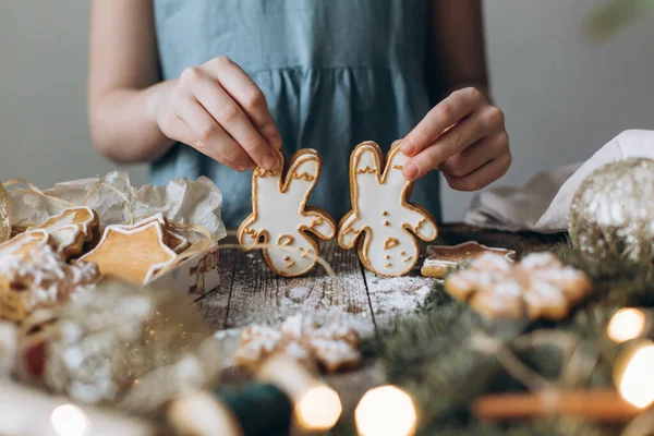 Children\'s hands play gingerbread man on the table among the Christmas decor of spruce branches and toys.