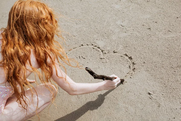 Red Haired Girl Bathing Suit Draws Sand Stick — Stock Photo, Image