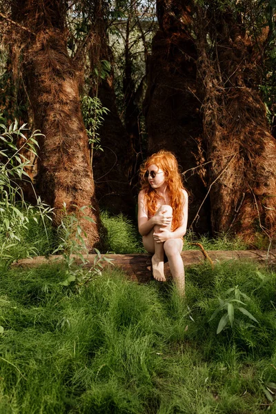 Рыжая Девушка Купальнике Задумчиво Сидит Среди Зелени Леса — стоковое фото