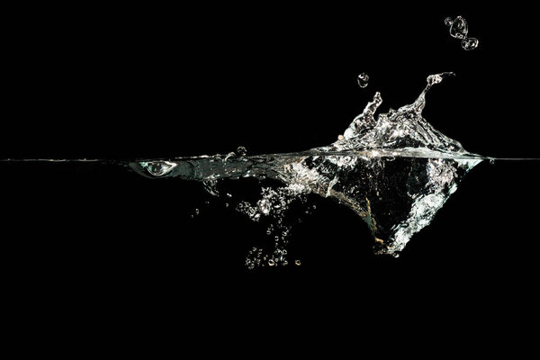 close up of water waves splash and bubbles isolated on black background.