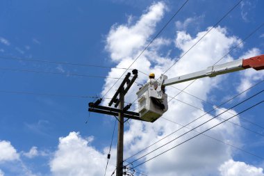 Bir mühendis ya da elektrikçi kova üzerinde çalışıyor. Yüksek voltajlı iletim hatlarını onarmak için..