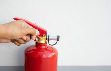 Beyaz arkaplanda insan eli yangın söndürme tüpü ve kopyalama alanı.