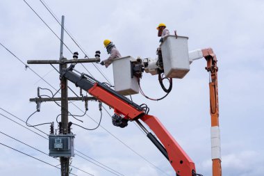 Elektrikçi yüksek voltaj iletim hatlarını korumak için kova vagon üzerinde çalışıyor..