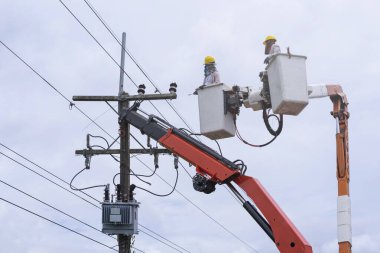 Elektrikçi, yüksek voltajlı nakil hatlarına kova vagon üzerinde çalışıyor..
