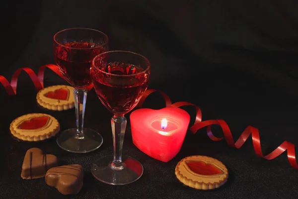 İki kristal kadeh şarap, mumlar ve tatlılar. Tutkunun rengi kırmızıdır. Romantik tarih. Benim sevgilim olmak