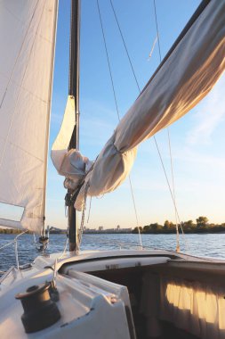 Gemi teçhizatı. Gün batımında beyaz yelkenler. Sakin. Yat nehirde yüzüyor.