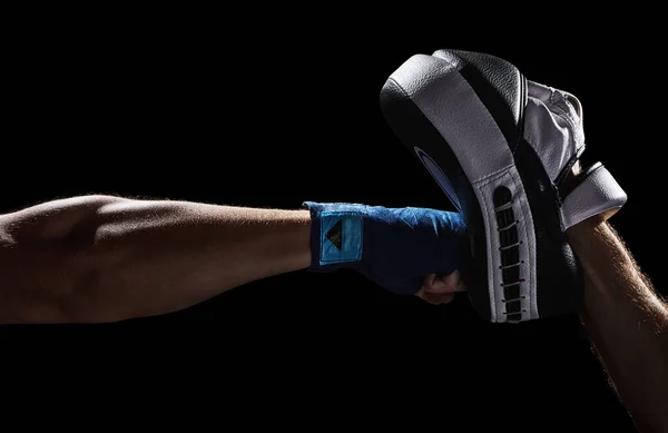 Punch Mitts 'e boks yumruğu. Antrenman alanı. Avcı atleti yumruğunu yumruk ve çıplak yumrukla vuruyor. Siyah bir arkaplanda izole edilmiş.