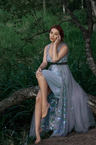 Красивая девушка в длинном платье в лесу — стоковое фото