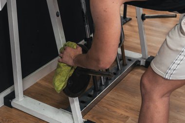 Onu kullandıktan sonra jimnastik makinelerini temizliyor.