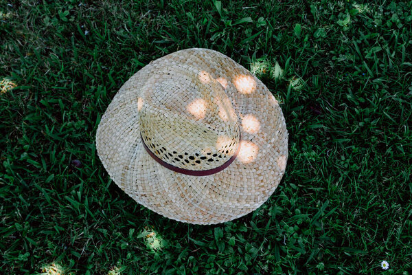 Straw hat on the green grass background in the shade