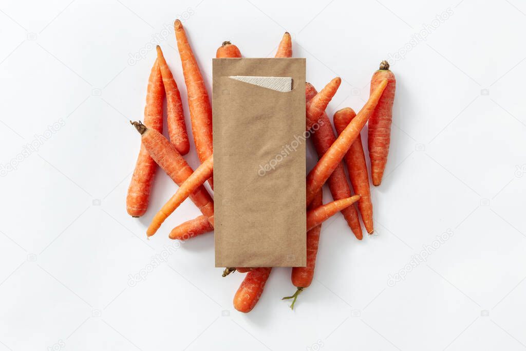 Take away brown kraft cutlery packaging and napkin with carrots on white background
