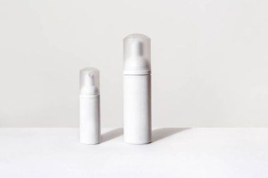 Beyaz arka planda kozmetik ürünleri için iki küçük ve büyük sprey şişesi.