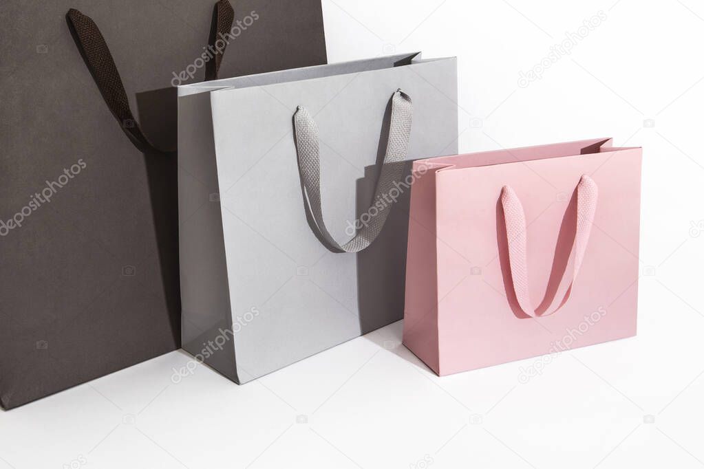 Big dark and light grey medium and pink small paper bags and shoppers