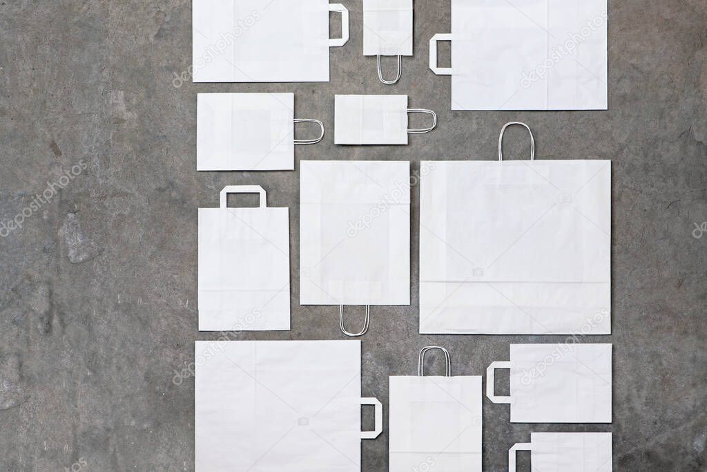 Composition of white paper bags of different size on concrete
