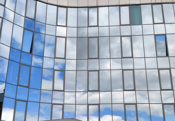 Modern building in the city with mirrored windows. Mirror wall with sky reflection.
