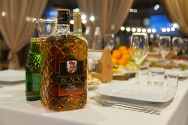 Tula, Rusya, 16, 12, 2017. Odaklanmış bir içki şişesi ve restoranın karanlık odasındaki bir masaya odaklanmamış bardaklar. Yazı.