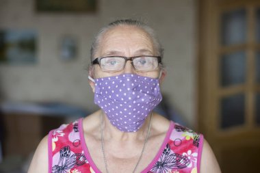 Koruyucu tıbbi maskeli yaşlı kadın ev karantinasında
