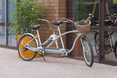 Bir yaz gününde, bir sokak kafesinin önünde gri ikili bisiklet.