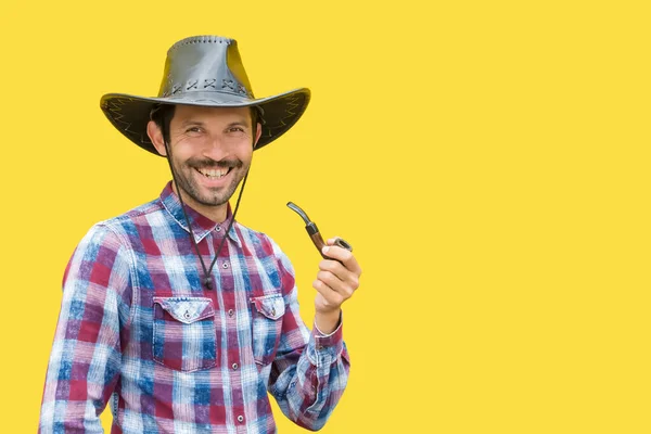 a man in a cowboy hat holds a smoking pipe