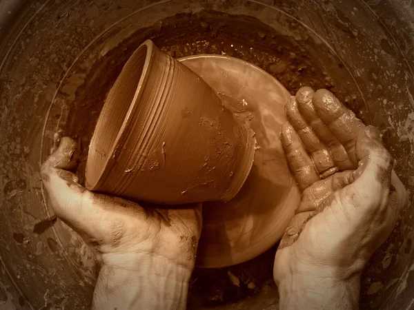 Çömlekçinin elleri nazikçe ve kesinlikle çömlekçinin tekerindeki kil çömlekten oluşur. Usta çömlekçi bir atölyede çalışıyor.