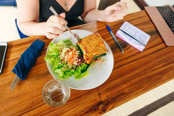 business girl eating vegan lasagna with salad in a cafe