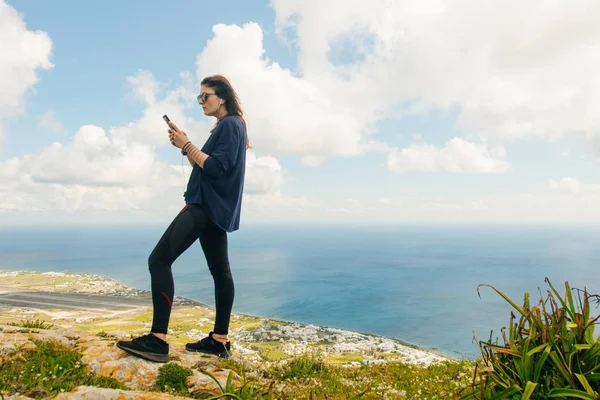 Κορίτσι κοιτάζει στο smartphone στο βουνό Σαντορίνη, Ελλάδα — Φωτογραφία Αρχείου