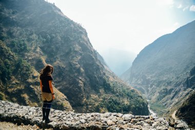 Tepede duran ve dağlara bakan genç bir kadın. Nepal 'de dağlarla, mutlu bir kızla manzara.