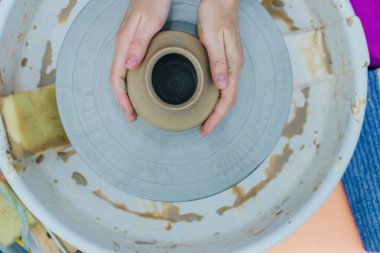 Çömlekçi çarkında çalışan kadınlar. Eller kilden bir kap yontuyor..