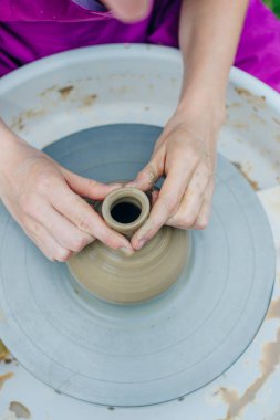 Çömlekçi çarkında çalışan kadınlar. Eller kilden bir kap yontuyor..