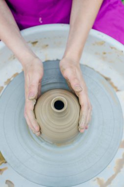 Çömlekçi çarkında çalışan kadınlar. Eller kilden bir kap yontuyor..