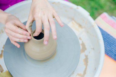 Çömlekçi çarkında çalışan kadınlar. Eller kilden bir kap yontuyor..