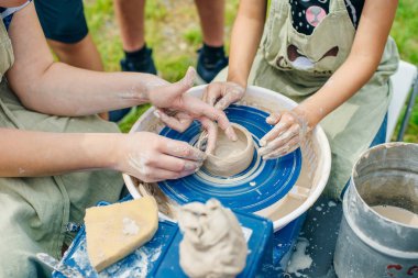 Çömlekçi çarkında çalışan kadınlar. Eller kilden bir kap yontuyor..
